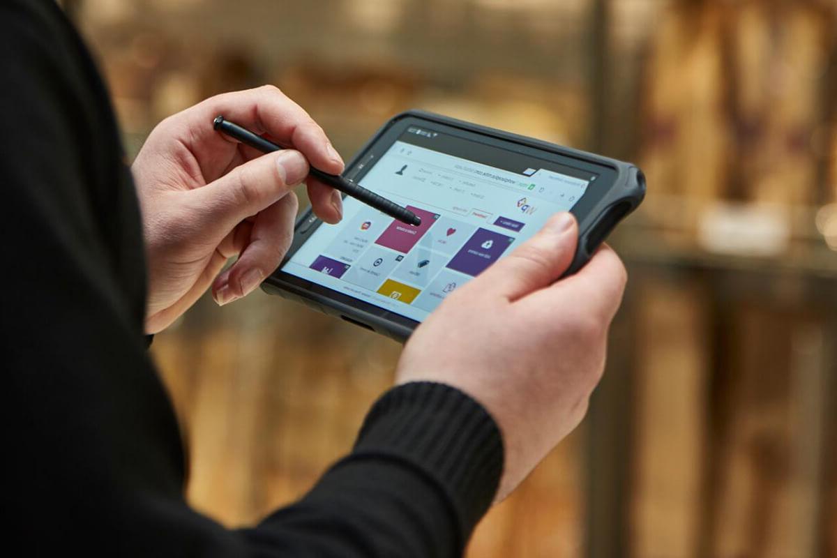 Male security guard in Sainsbury's using Mitie's Merlin security 科技nology system with a stylus